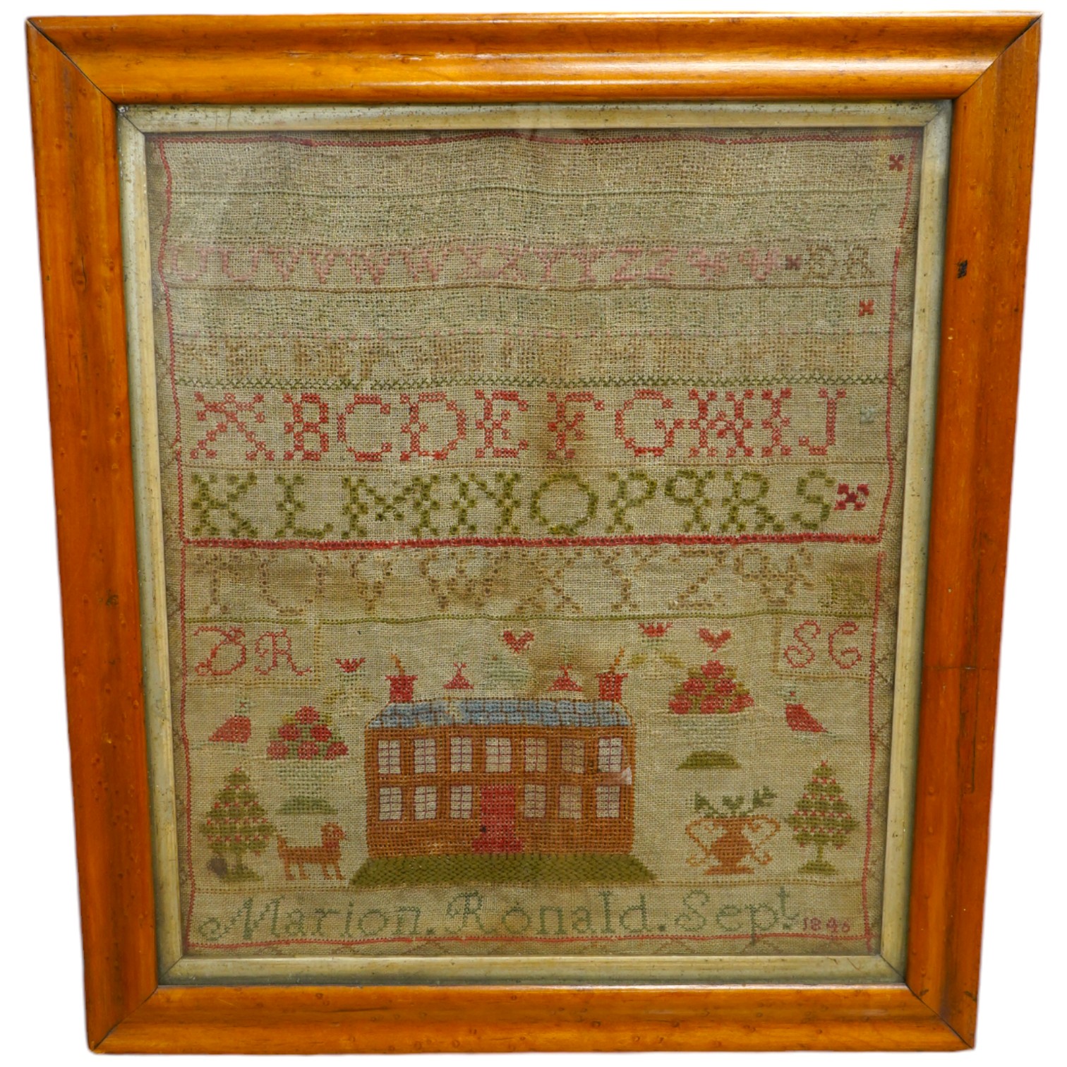 A 19th century sampler by Marion Ronald dated 1846, worked with various alphabets in cross stitch and buttonhole stitch, the lower section depicting a large thirteen windowed house surrounded by various spot motifs, a do